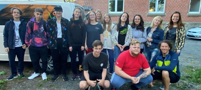 Gruppenbild von 11 Jugendlichen mit ihrer Betreuerin und ihrem Betreuer neben dem VW-Bus der Gemeinde Lohfelden.