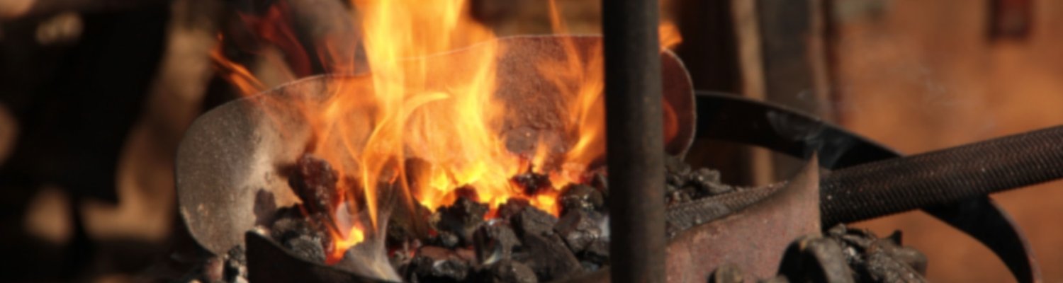 Blick in eine Schmiedewerkstatt mit offenen Feuer und glühendem Eisen.
