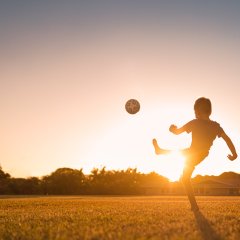 Boy playing soccer at sunset.