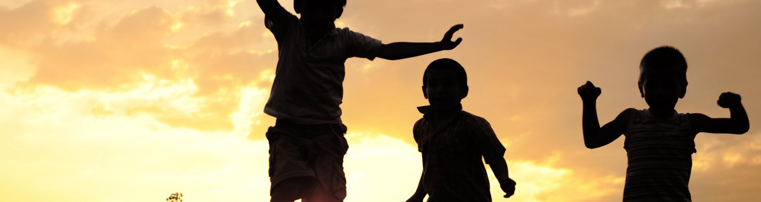 Children running on meadow at sunset
