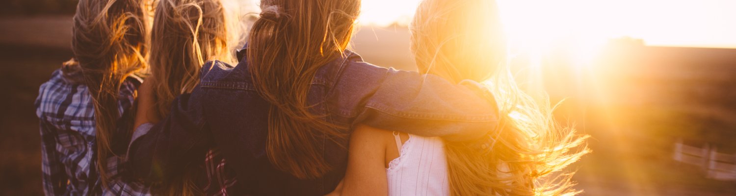 Teen girls facing the sunset with on a summer evening