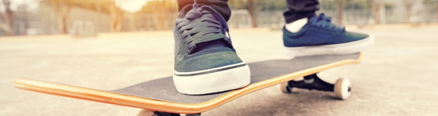 Beine in Sneakers auf einem Skateboard