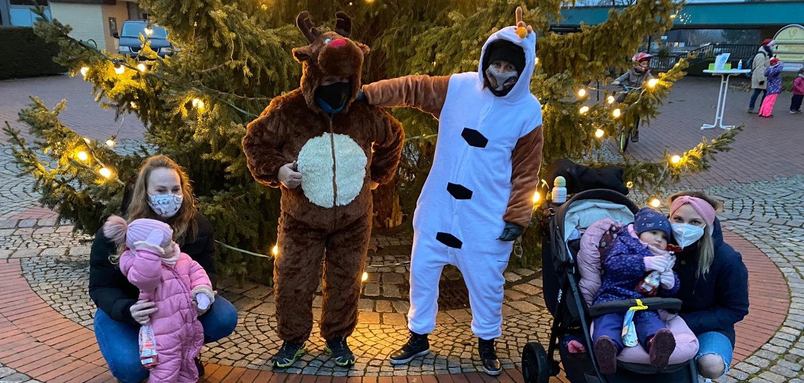 Mütter mit Kindern vor dem großen Weihnachtsbaum mit Helfern des Nikolauses